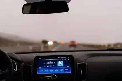 Interno di un'auto elettrica con le mani del conducente al volante e il paesaggio urbano sullo sfondo