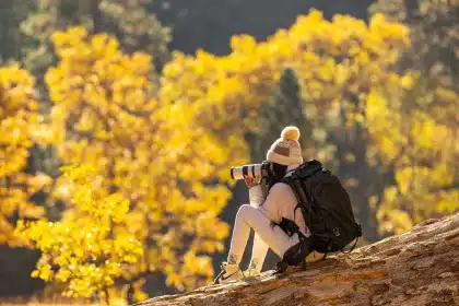 Mani di fotografo con fotocamera 35mm riprendono paesaggio con fasce di colore saturi e forme geometriche