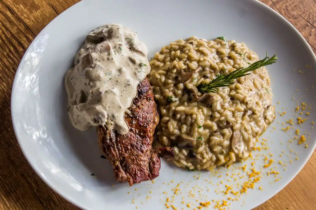 Piatto di risotto cremoso su tavolo rustico con ingredienti lombardi