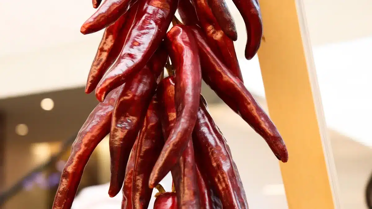 Cucchiaio che versa salsa speziata su salsiccia