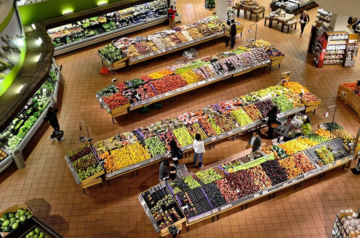 Scaffali di supermercato con snack generici davanti a una vetrina di ristorante quasi vuota