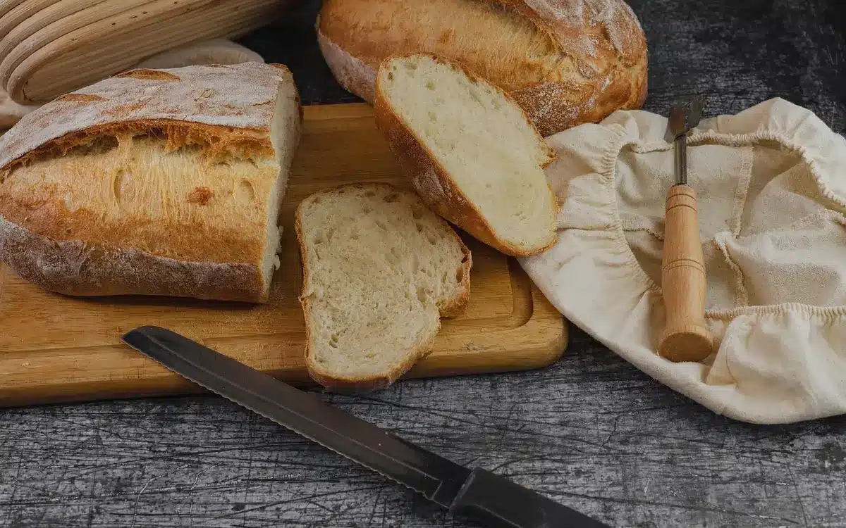 Mani che sistemano pasticceria artigianale su un tavolo di legno in una sala mercato soleggiata