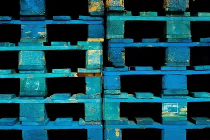 Pallets di libri impilati in un magazzino, operatore con transpallet sullo sfondo