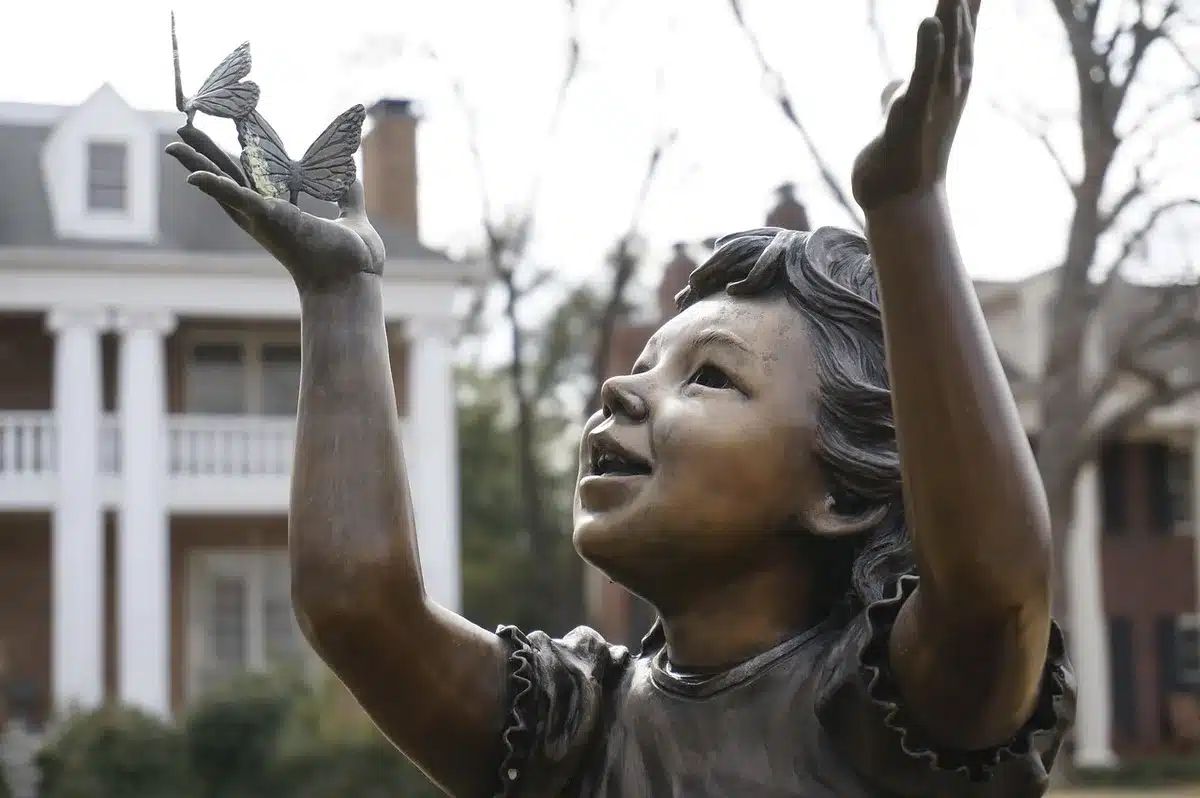 Mano che tiene una piccola statuetta di bronzo per mostrare la scala