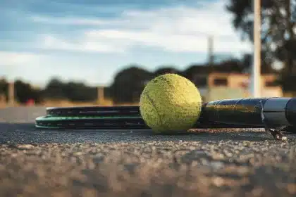 Campo da tennis vuoto con racchette e borsa in primo piano, atmosfera di attesa